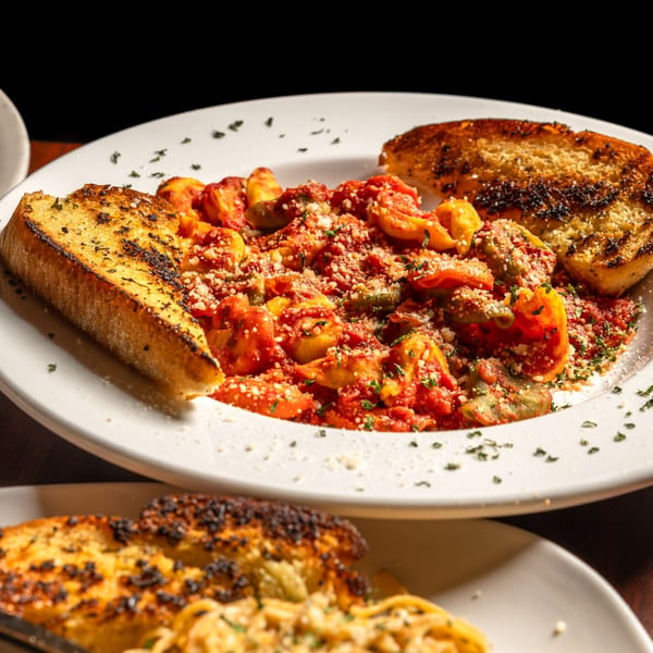 Gusto Dolce Italian Bistro's pasta dish with red sauce, shrimp, and two pieces of garlic bread.