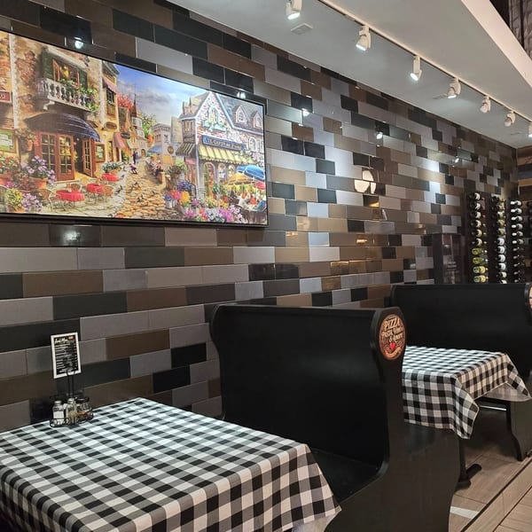 Cozy Gusto Dolce Italian Bistro interior with checkered tables, dark booths, and a large Italian street scene painting.