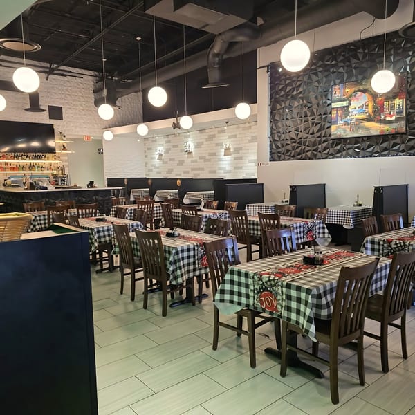 Interior of Gusto Dolce Italian Bistro with checkered tablecloths, wooden chairs, and a bar area.